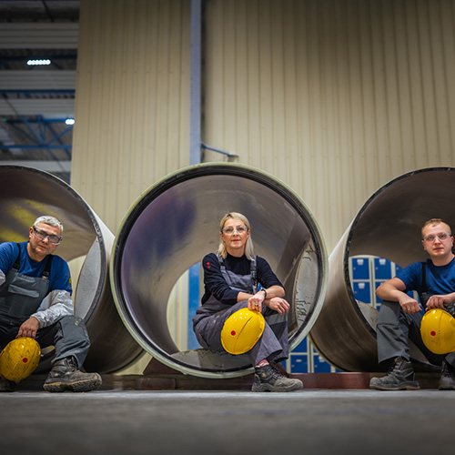 blue-collar workers sitting inside GRP pipes at Amiblu factory in Poland