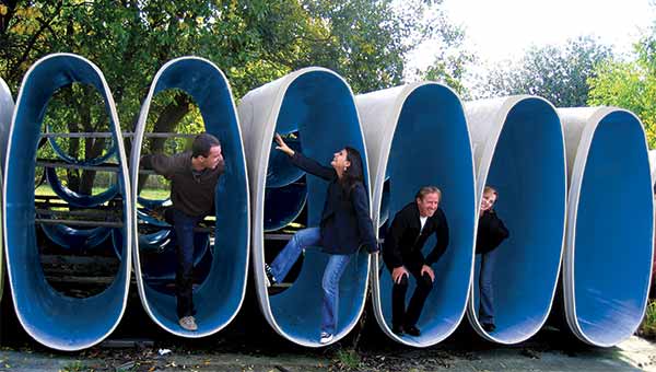 People in non-circular pipes smiling and fooling around